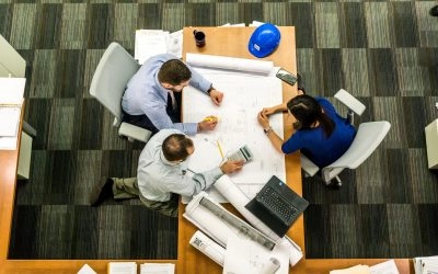 Three engineers working on a project at a desk.